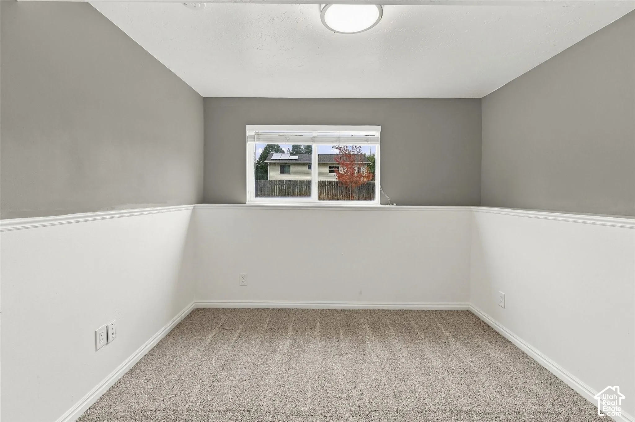 Carpeted flooring, neutral wall colors, window with white trim, and a flush mount ceiling light fixture