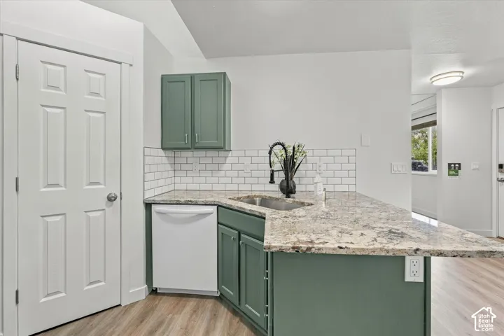 Granite countertops, subway tile backsplash, matte black faucet, wood-finish flooring, and recessed lighting