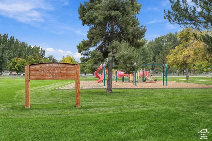 Grassy park area featuring a wooden park sign and playground equipment