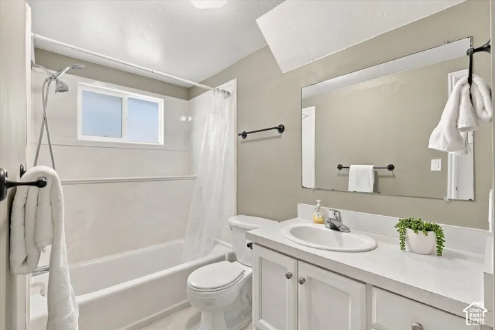 Bathroom featuring a shower-over-tub combination, vanity with integrated sink, white cabinetry, and a large wall-mounted mirror