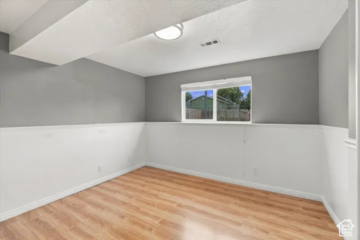 Wood-finish flooring, two-tone wall treatment, overhead lighting, and a window for natural illumination