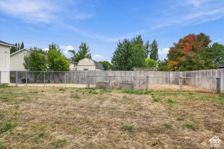 Spacious fenced yard featuring a chain-link fence, wood privacy fence, and a structured enclosure