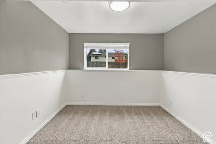 Carpeted flooring, neutral wall colors, window with white trim, and a flush mount ceiling light fixture