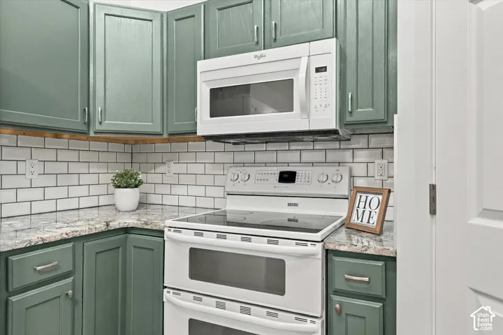 Kitchen featuring a double oven range, built-in microwave, subway tile backsplash, green cabinetry, and light-toned countertops