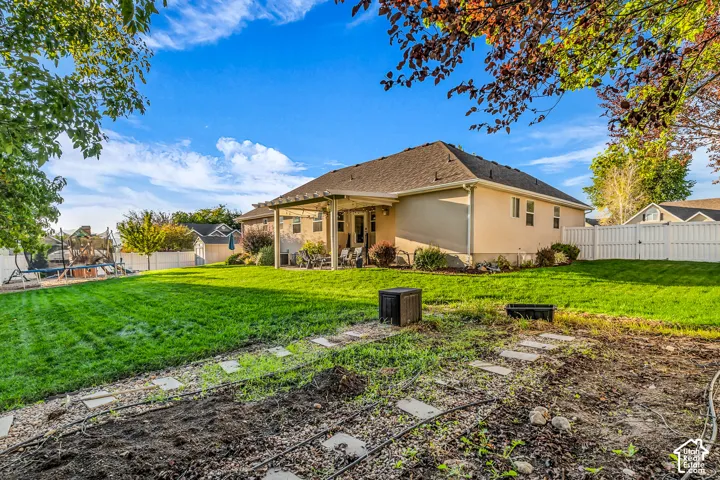 Expansive backyard featuring a manicured lawn, a covered patio, and a white privacy fence