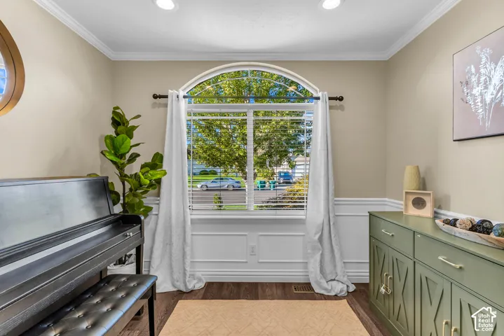 Arch-top window with blinds, wood-finish flooring, wainscoting detail, recessed lighting, and crown molding