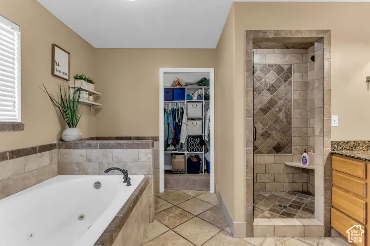 Soaking tub with tiled surround, walk-in shower with built-in bench and glass enclosure, and tiled flooring