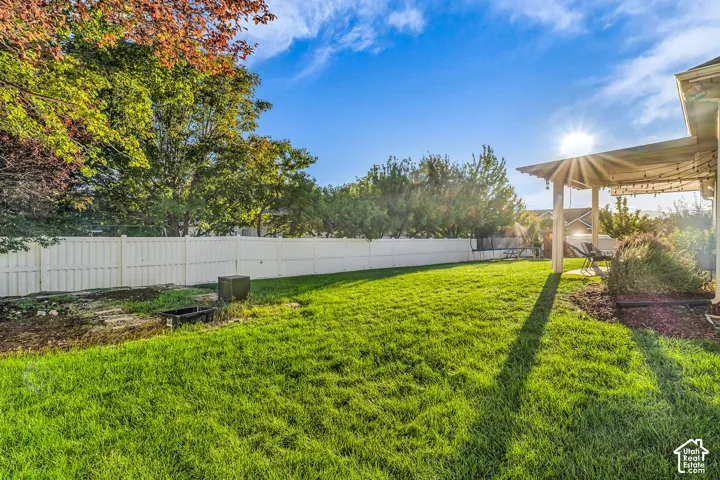 Manicured lawn with a white privacy fence and mature trees