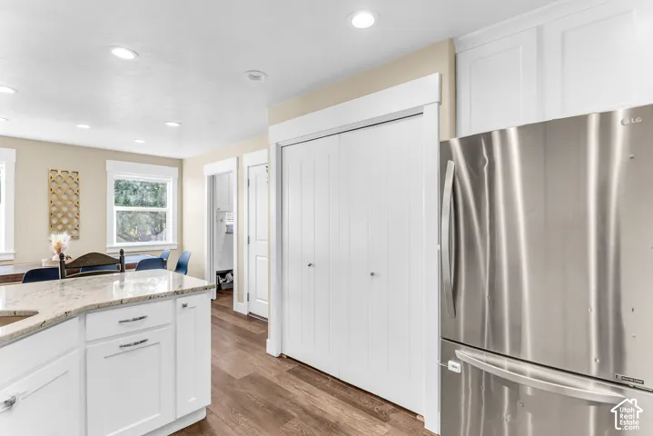 Kitchen featuring white cabinetry, light-toned countertops, wood-finish flooring, recessed lighting, and a stainless steel refrigerator