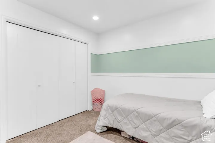 White bi-fold closet doors, recessed ceiling lighting, light-colored carpeting, and a two-tone wall finish with decorative trim