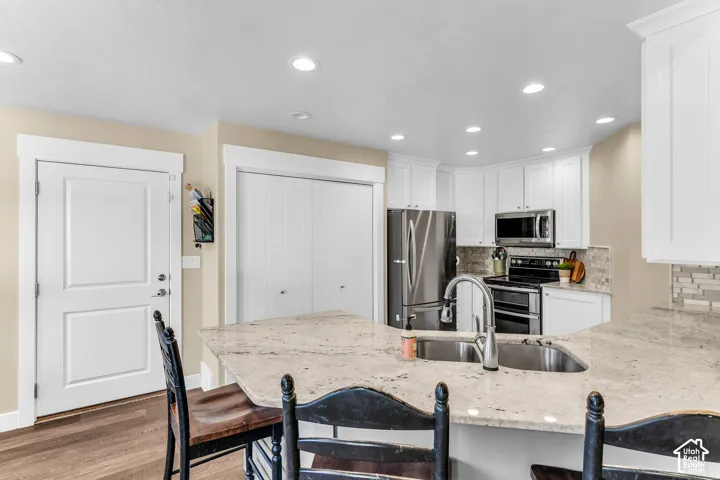 Kitchen featuring a stainless steel double sink, light-toned countertops, white cabinetry, and recessed lighting