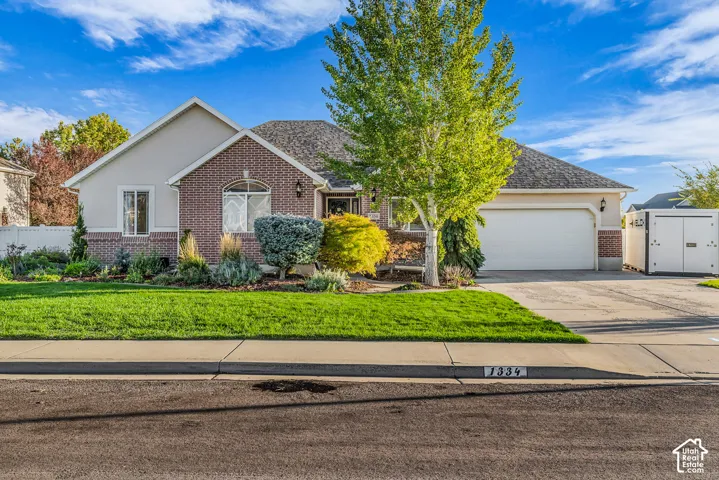 Brick and stucco exterior with an arched window, attached garage, and a lush lawn