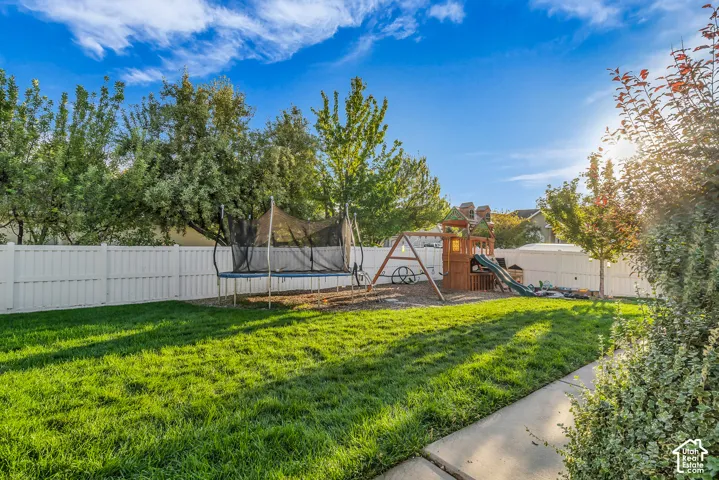 Expansive backyard featuring a manicured lawn, mature trees, and privacy fencing
