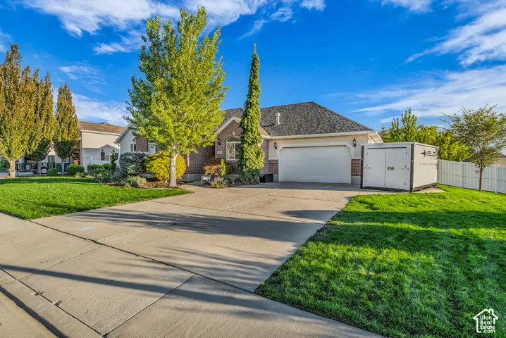 Brick and stucco exterior with an attached two-car garage, concrete driveway, and a white privacy fence
