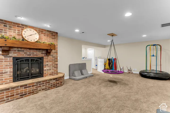 Brick fireplace with wood mantel, recessed lighting, and neutral wall paint