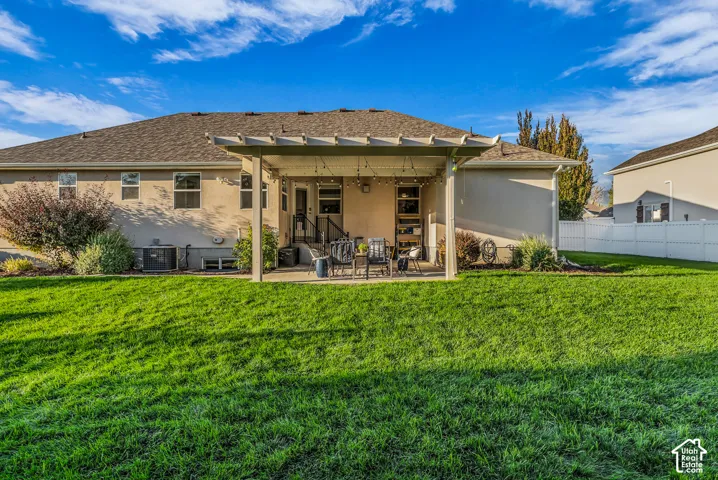Expansive backyard featuring a manicured lawn, a large patio with a pergola, and mature landscaping