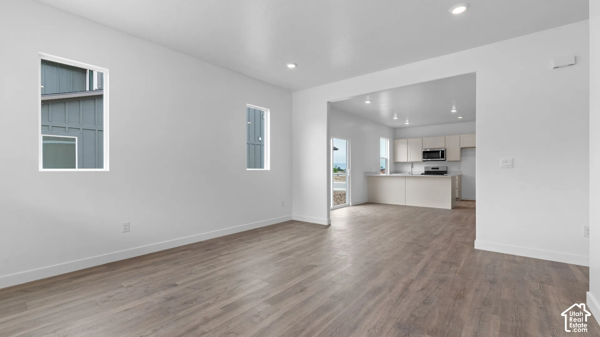 Wood-finish flooring throughout, recessed lighting, and a kitchen featuring a peninsula with seating