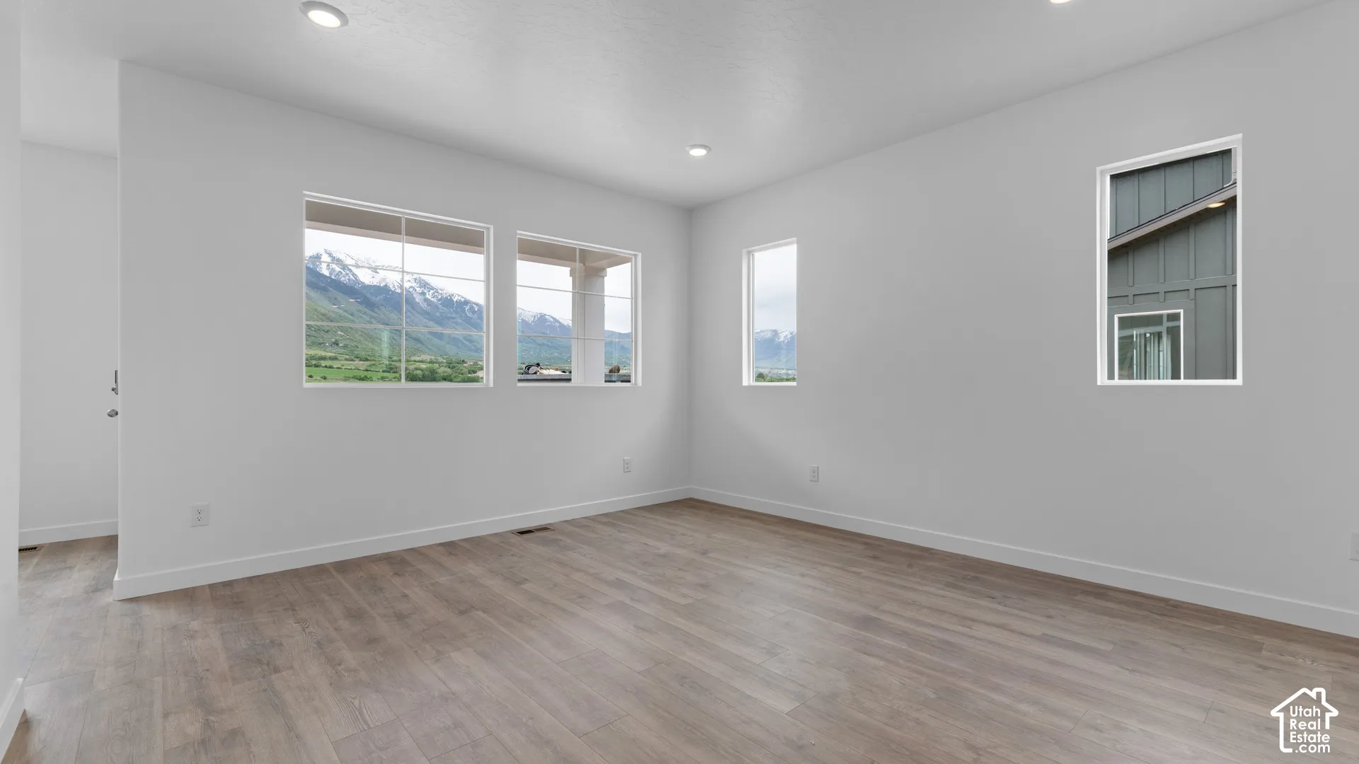 Recessed lighting, light wood-finish flooring, multiple windows, and white walls