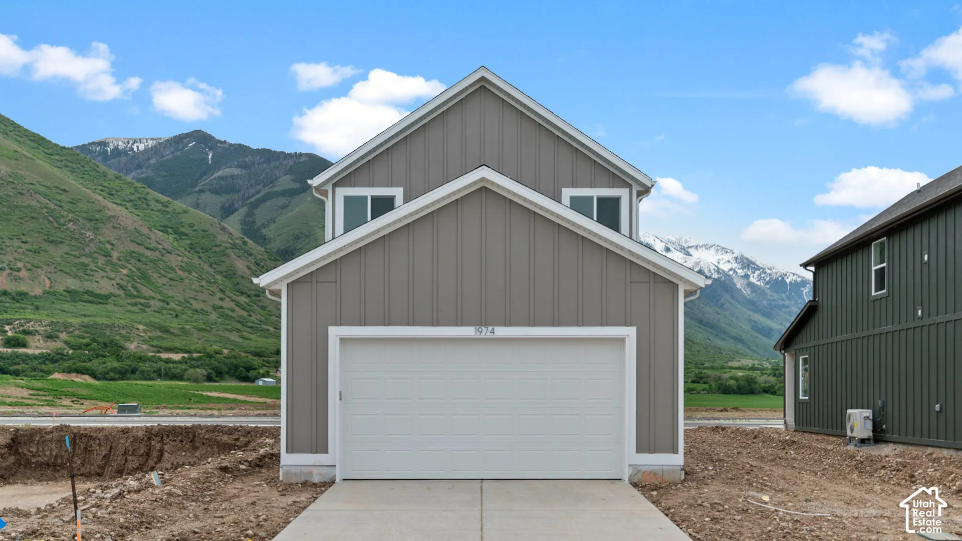 Vertical siding exterior with a prominent two-car garage and a mountain backdrop