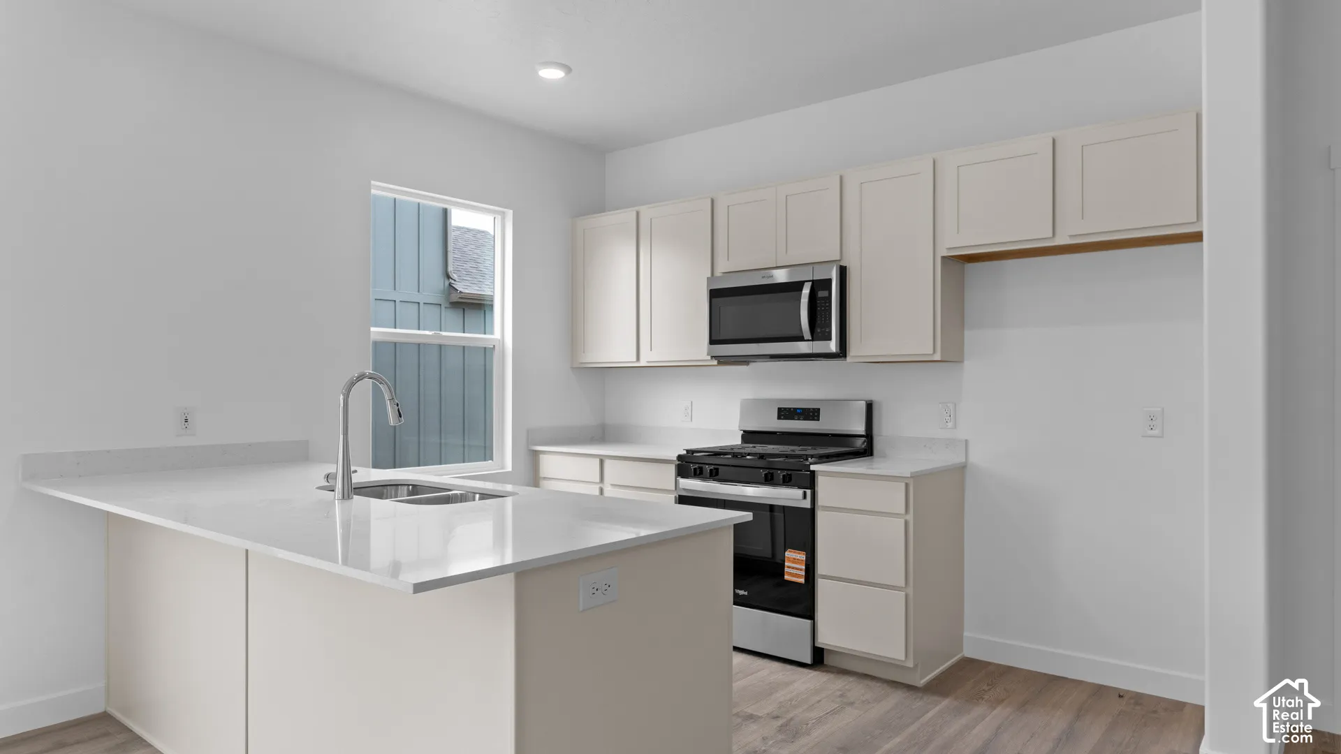 Light-filled kitchen with an island featuring an integrated sink and gooseneck faucet
