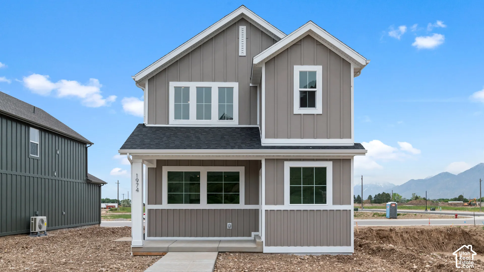 Two-story exterior featuring vertical and horizontal siding, a covered front entry, and multiple windows with white trim