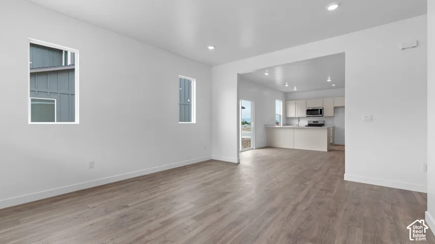 Wood-finish flooring throughout, recessed lighting, and a kitchen featuring a peninsula with seating