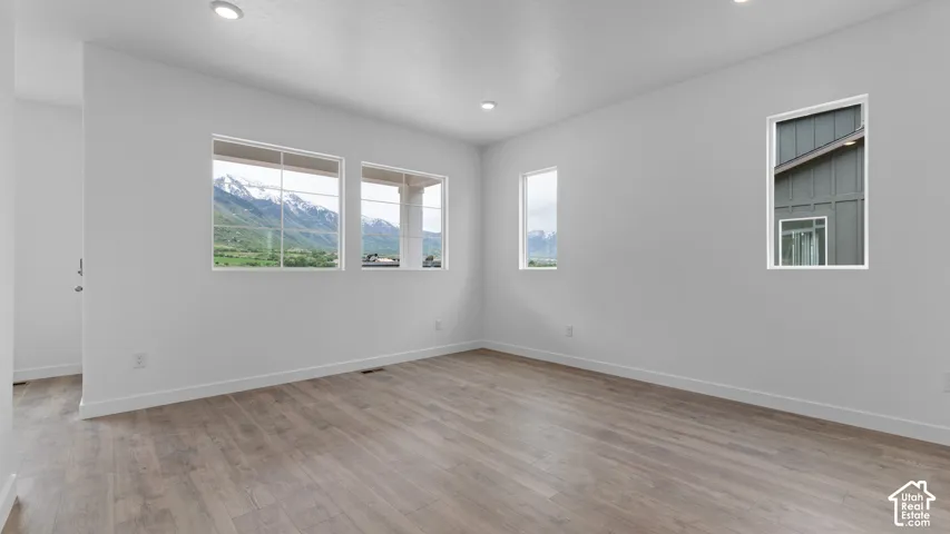 Recessed lighting, light wood-finish flooring, multiple windows, and white walls