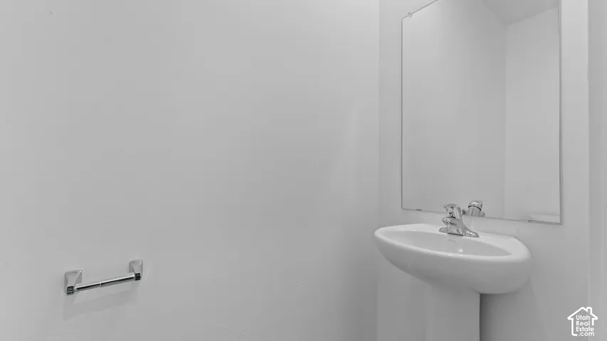 Pedestal sink with chrome faucet and rectangular wall-mounted mirror