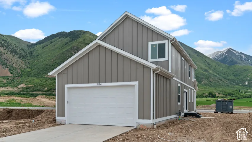 Two-story residence featuring vertical siding, white trim, and a two-car garage