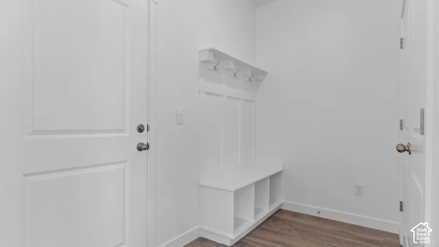 Built-in storage bench with cubbies, white paneling, and four coat hooks