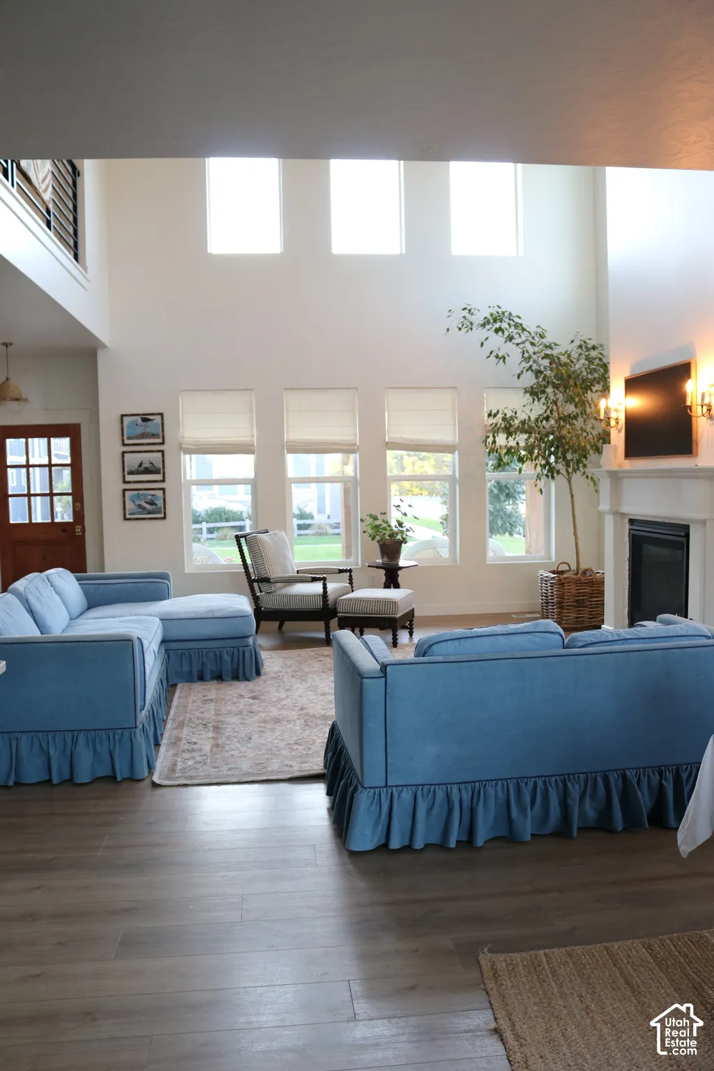 Two-story great room with a fireplace, a wood mantle, and sconce lighting