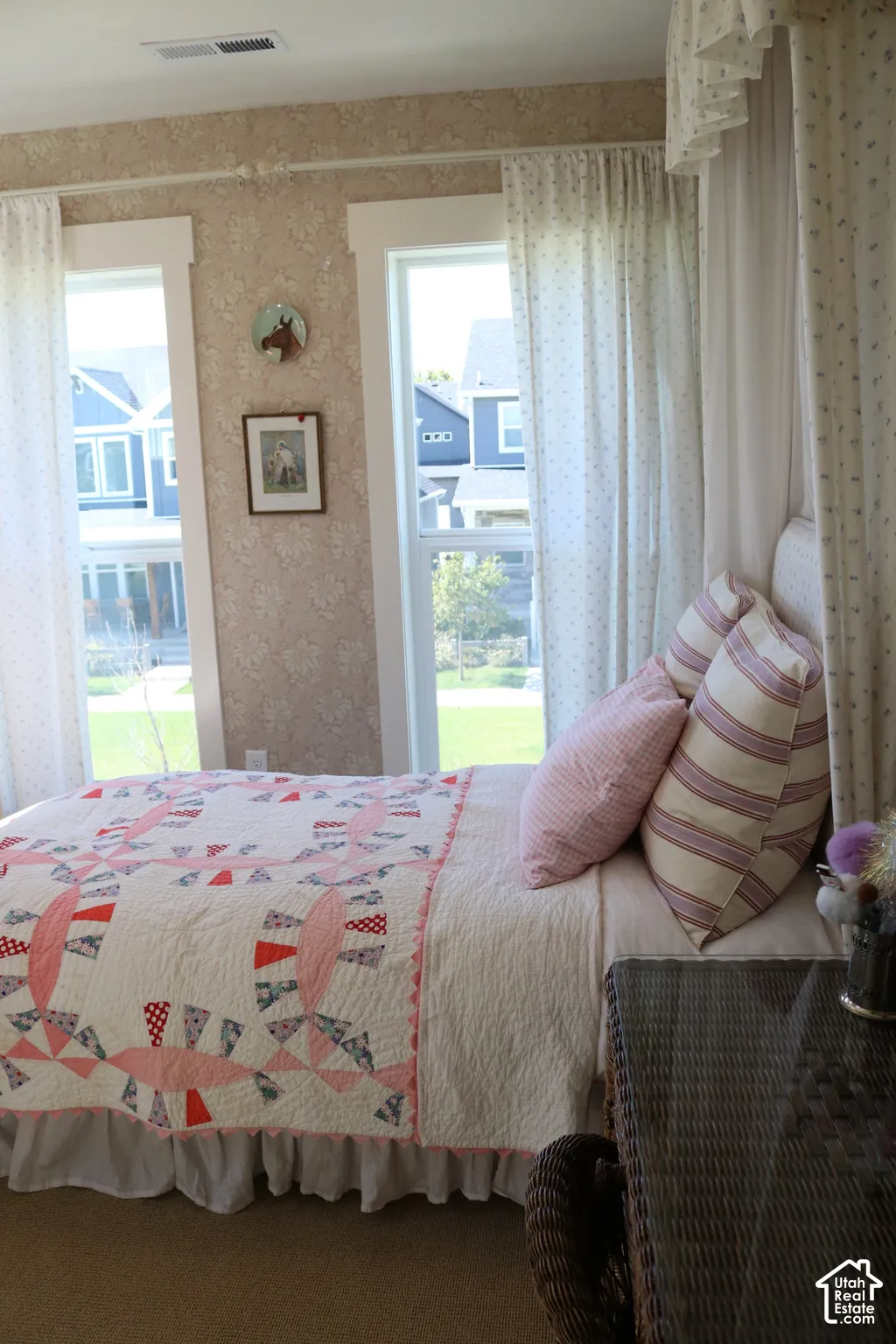 Two large windows with white trim, wallpapered walls, and neutral carpet flooring