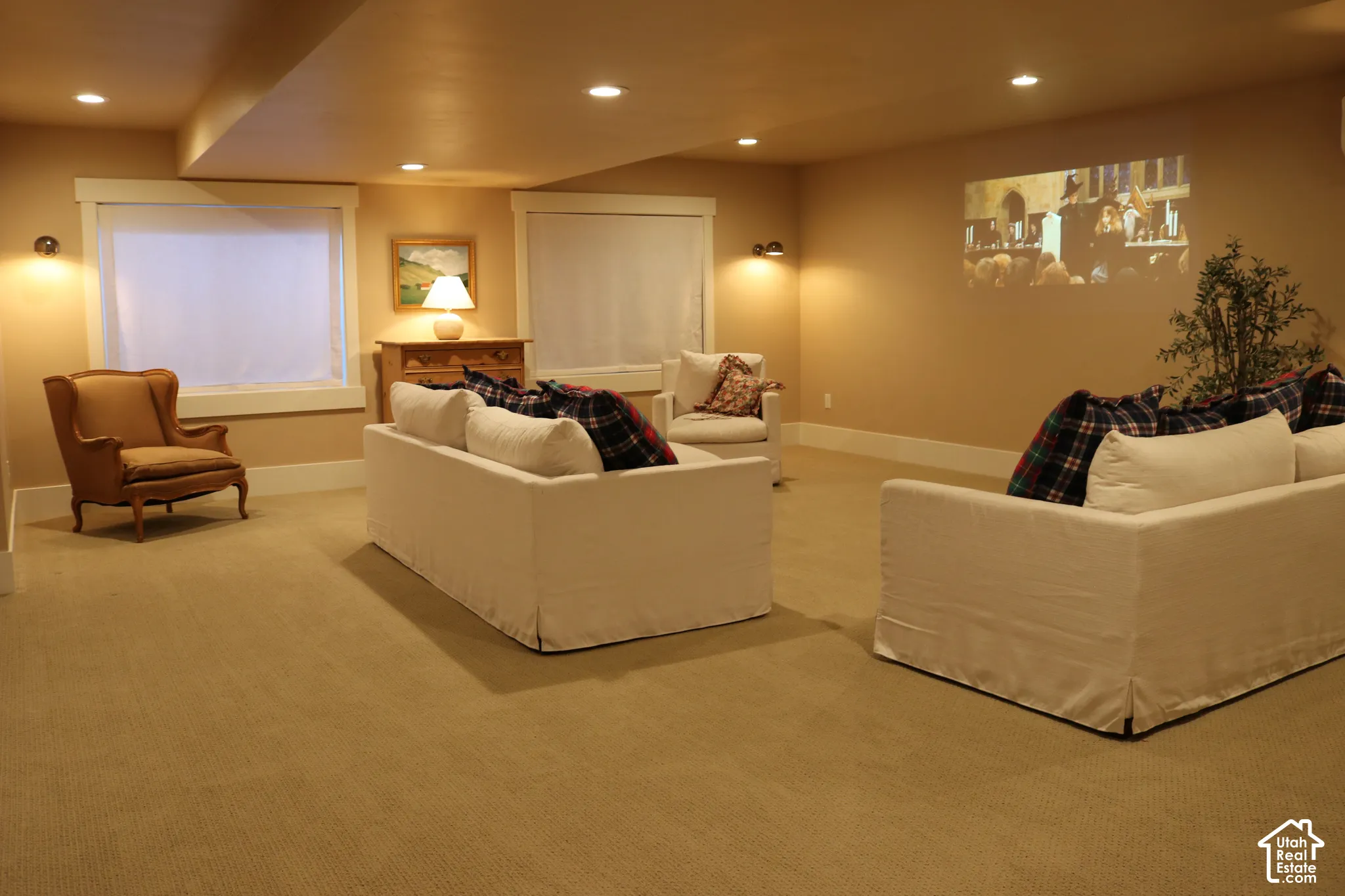 Recessed lighting illuminates a spacious room featuring a built-in projector display