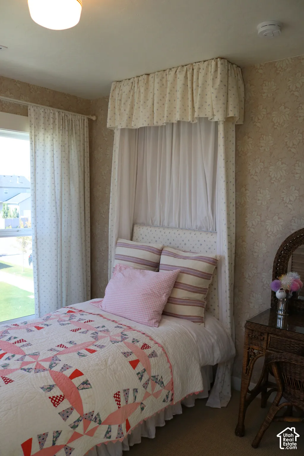 Patterned wallpaper, window with natural light, canopy bed frame, built-in light fixture, neutral carpeting
