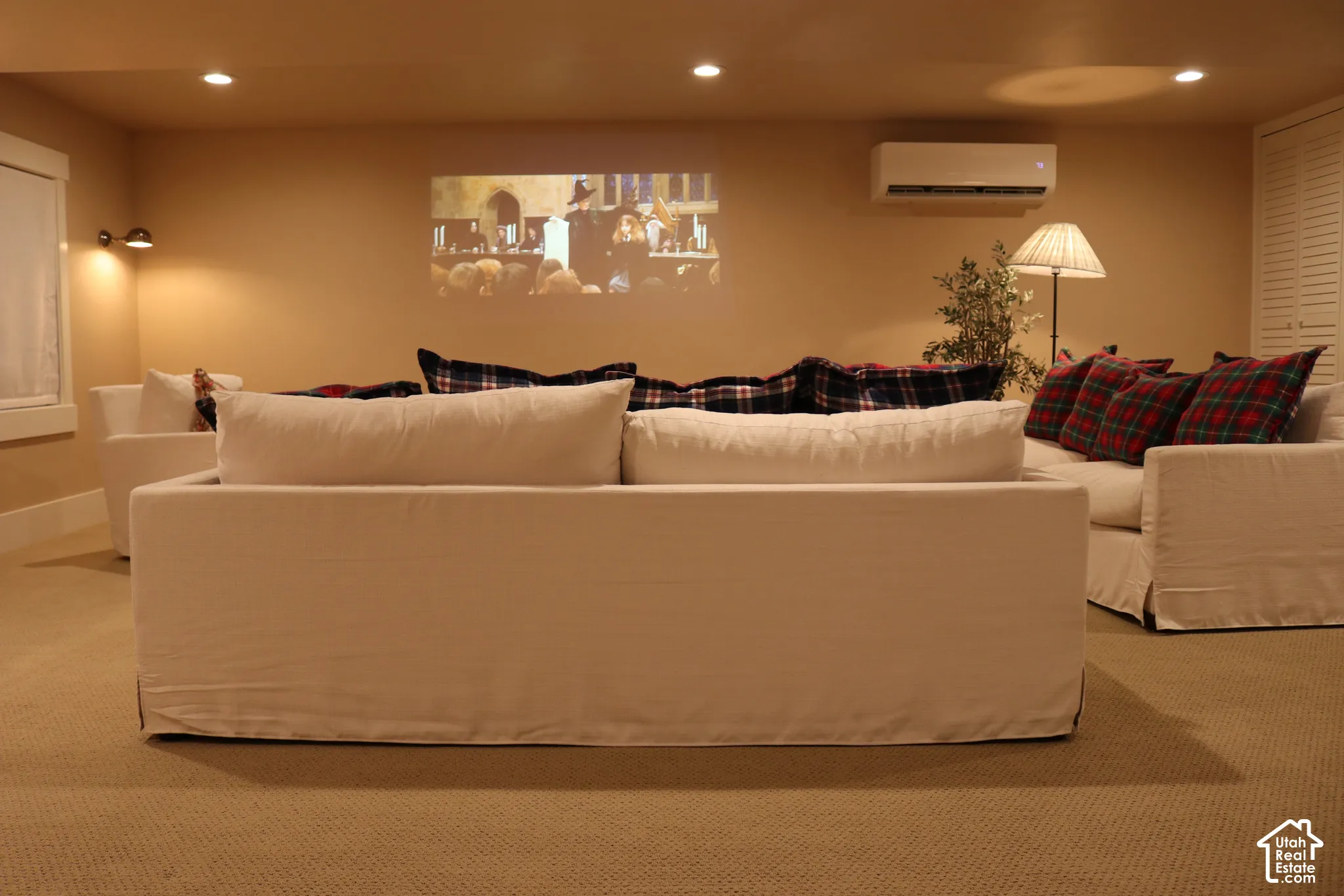 Recessed lighting, wall-mounted air conditioning unit, window with white trim, built-in louvered doors, and light-colored carpeting