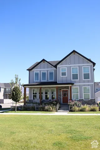 Two-story residence featuring light gray siding, dark trim, and a covered porch with natural wood posts