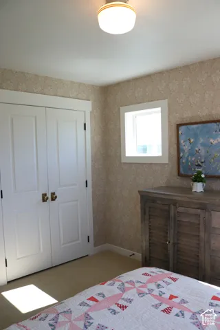 Patterned wallpaper, white trim, compact window, flush mount ceiling fixture, and carpeted flooring