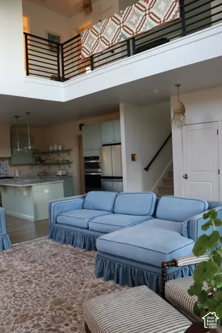 Open-concept living area with a double-height ceiling, kitchen island, stainless steel appliances, and wood-finish flooring