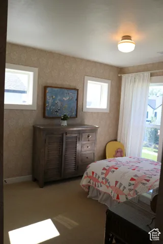 Textured wall covering, neutral carpeting, recessed windows, built-in ceiling light fixture, and a solid wood dresser