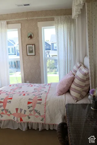 Two large windows with white trim, wallpapered walls, and neutral carpet flooring