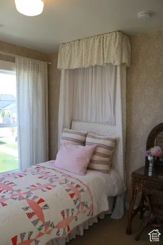 Patterned wallpaper, window with natural light, canopy bed frame, built-in light fixture, neutral carpeting
