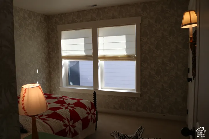 Two pane window with white trim, patterned wallpaper, and light-colored carpeting