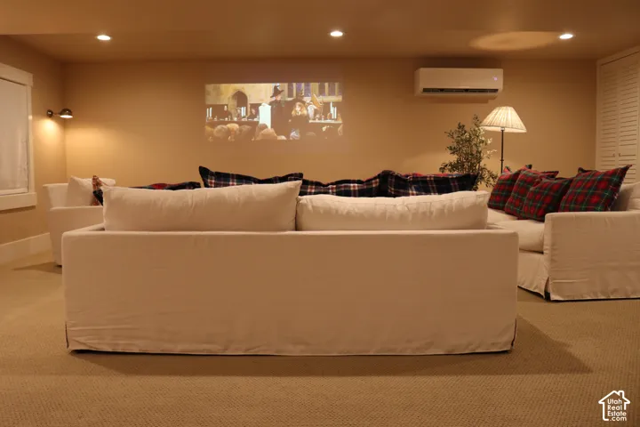 Recessed lighting, wall-mounted air conditioning unit, window with white trim, built-in louvered doors, and light-colored carpeting