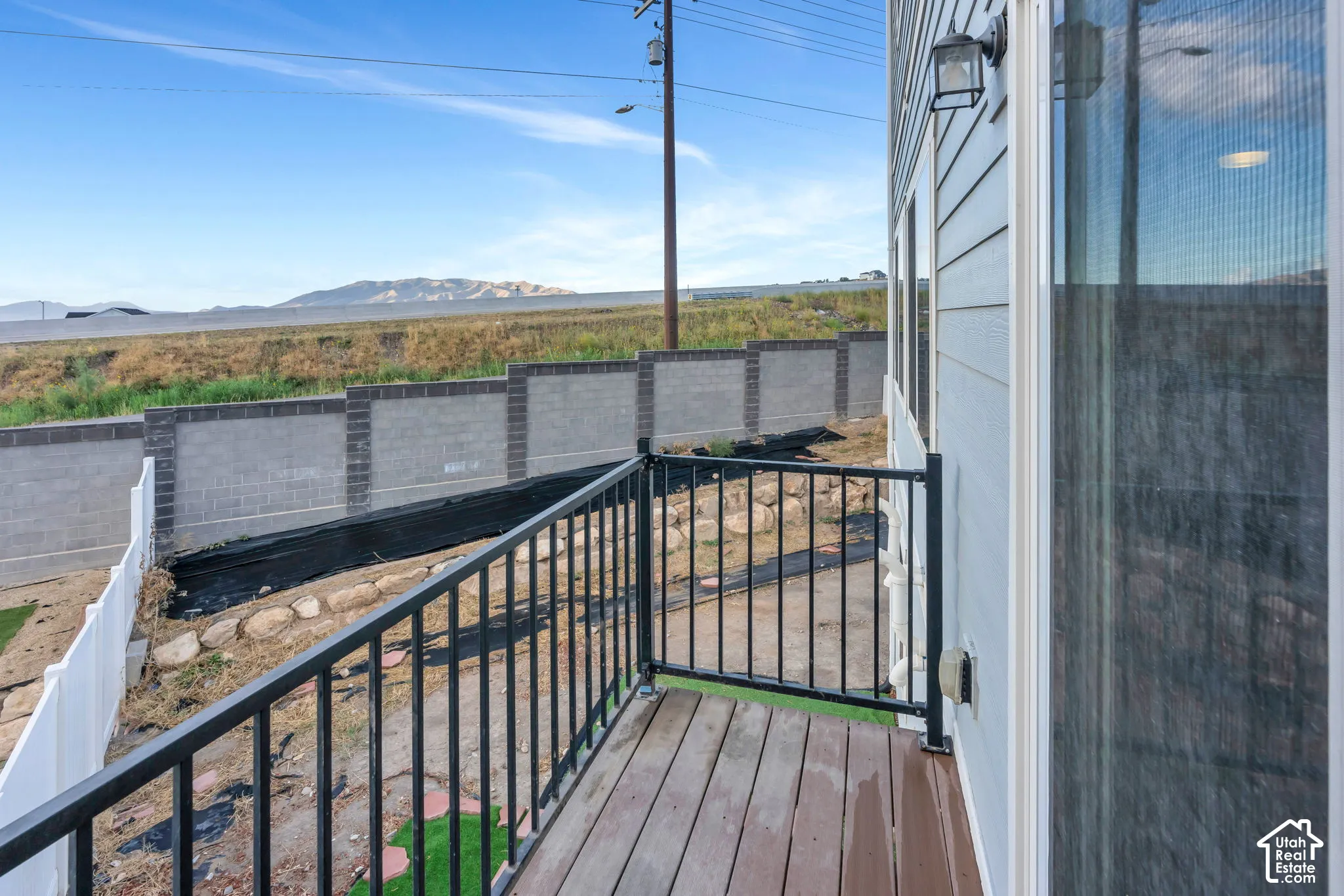 Private balcony featuring composite decking, black metal railings, and light gray siding