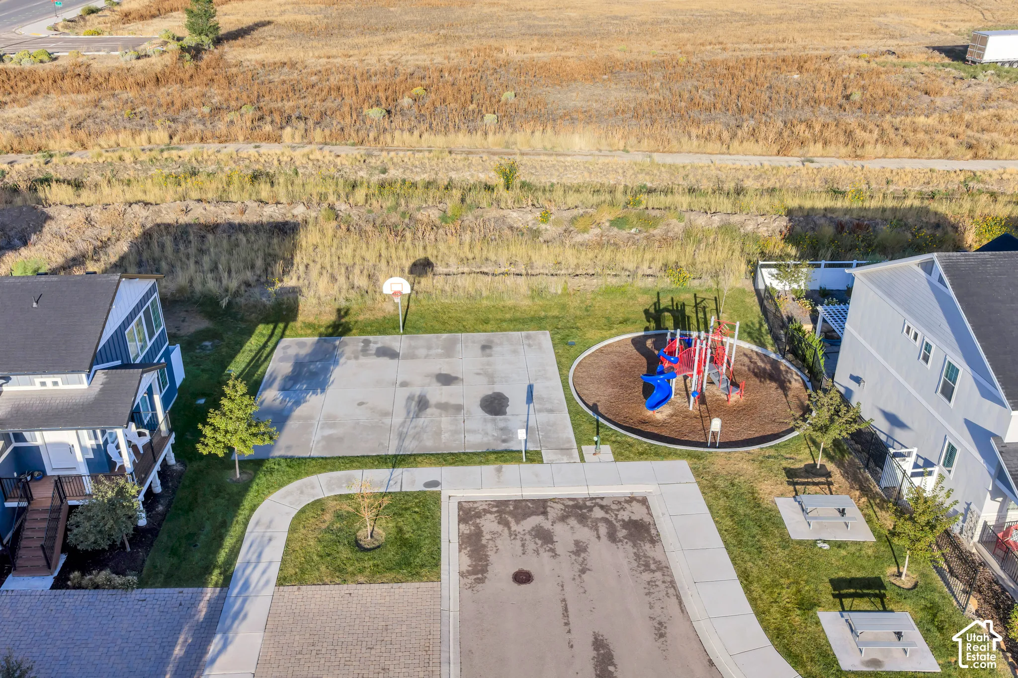 Community park area featuring a basketball court, playground, and picnic tables