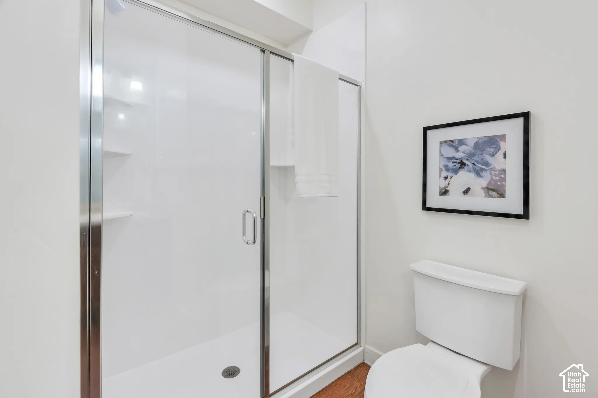 White shower enclosure with clear glass sliding door and integrated shelving