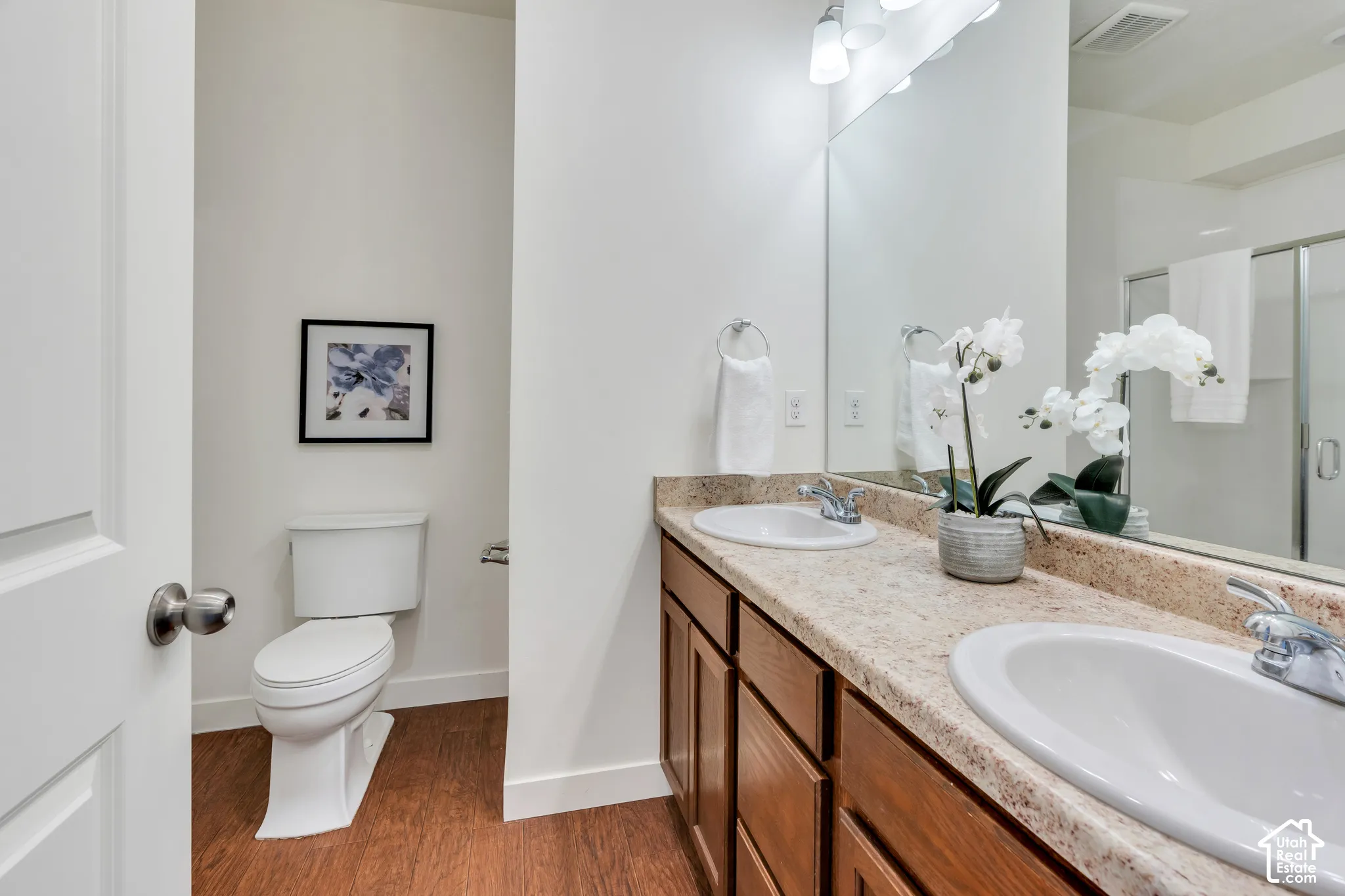 Dual vanity with integrated sinks, wood-finish cabinetry, and a large wall-mounted mirror