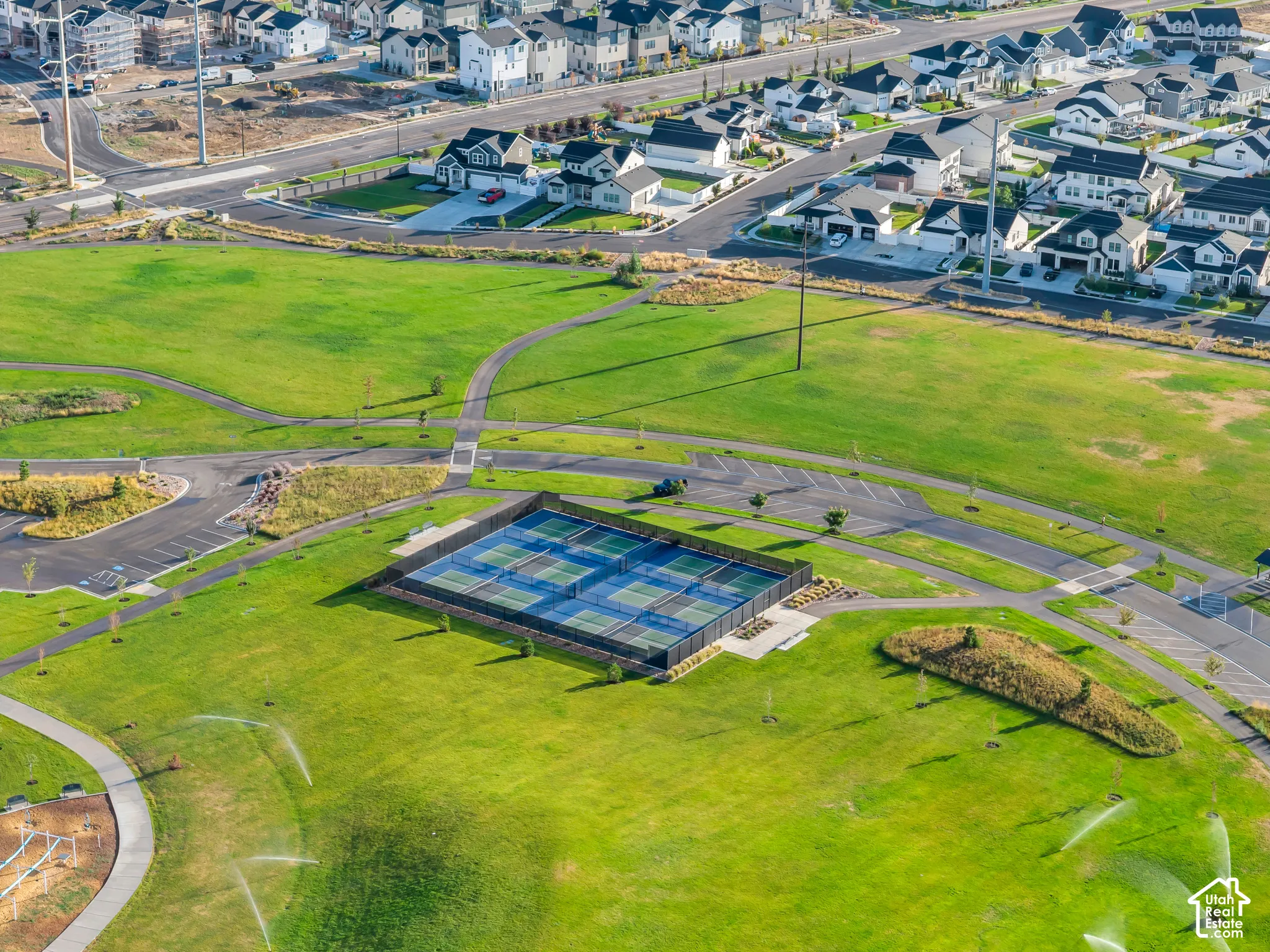 Expansive green spaces with paved pathways and tennis courts