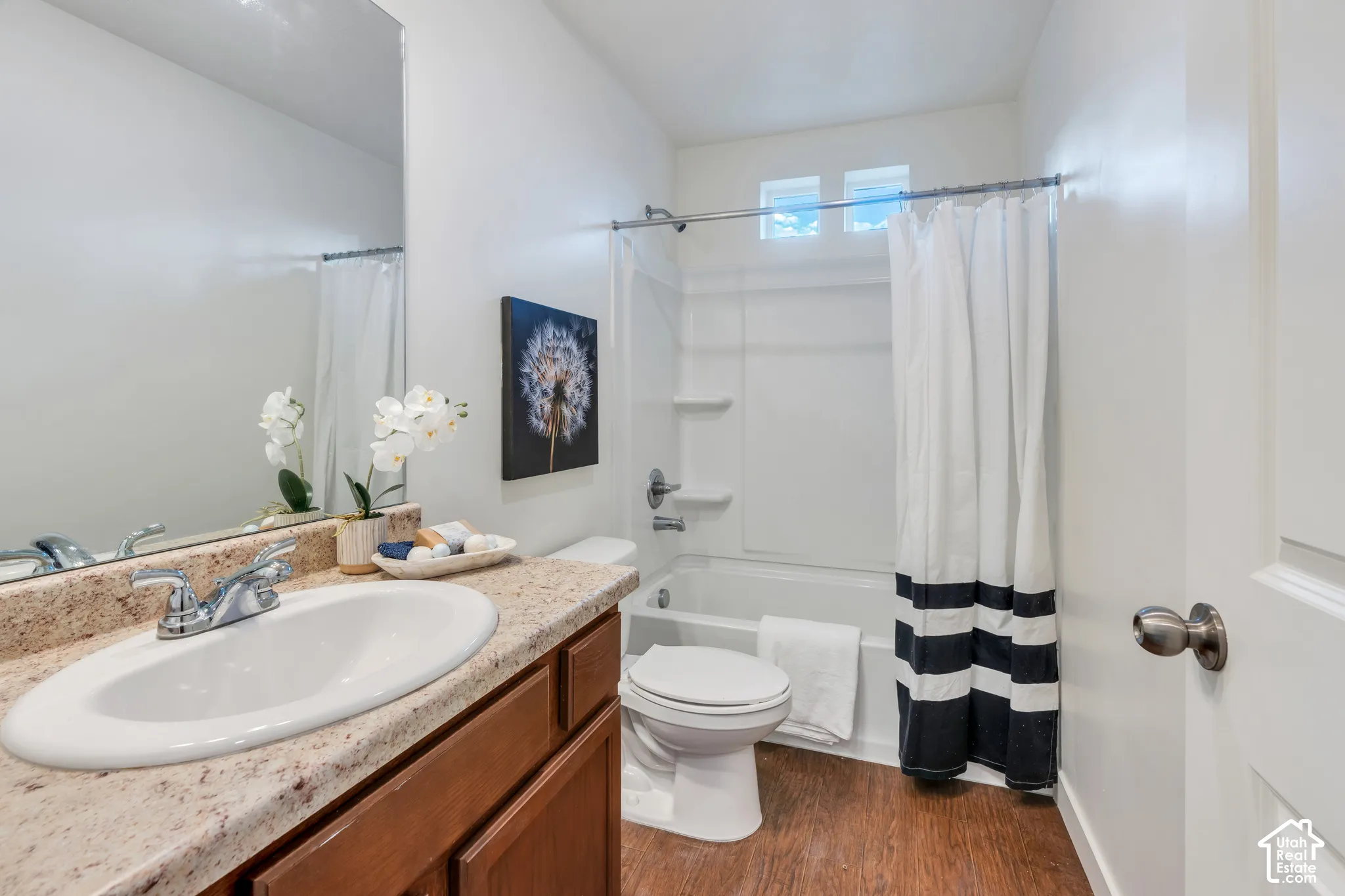 Bathroom featuring a vanity with a large mirror, a chrome faucet, and a stone-finish countertop