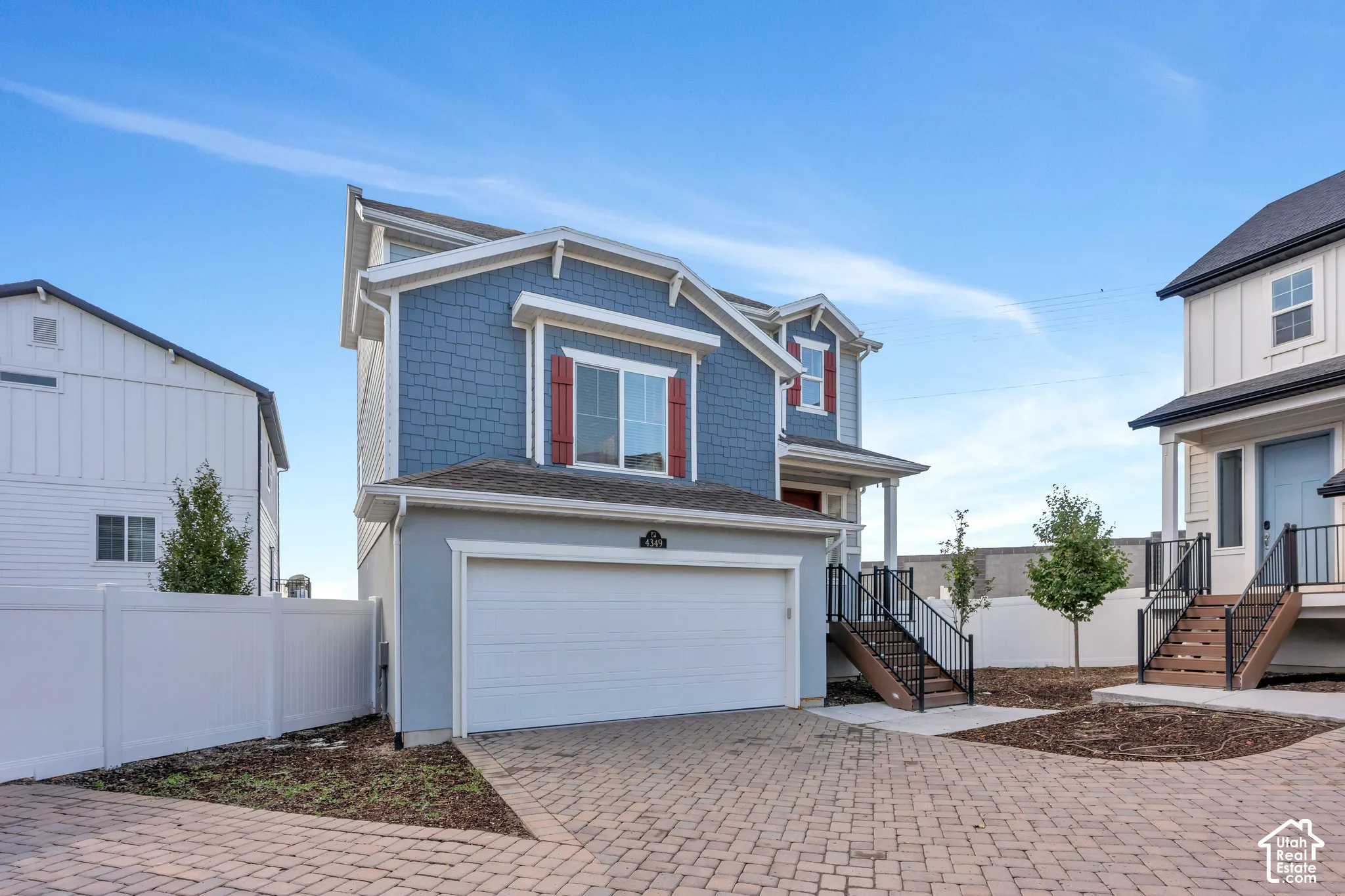 Two-story residence featuring a two-car garage, red window shutters, and a front porch